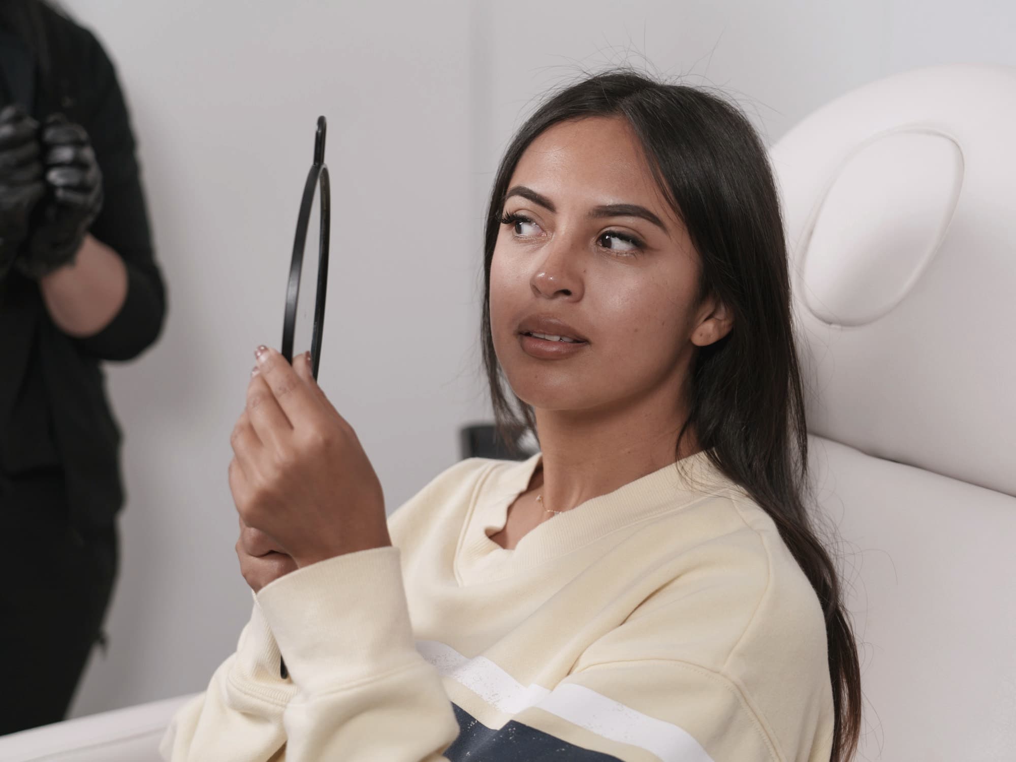 Client reviewing her skin in a hand mirror after a treatment
