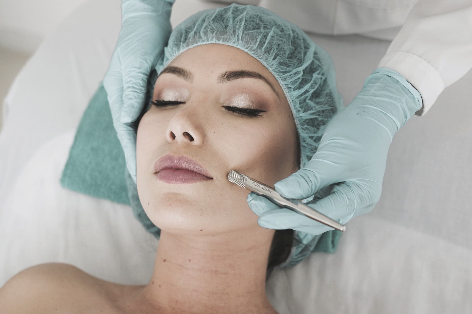 Dermaplaning blade used on the cheek by a gloved practitioner